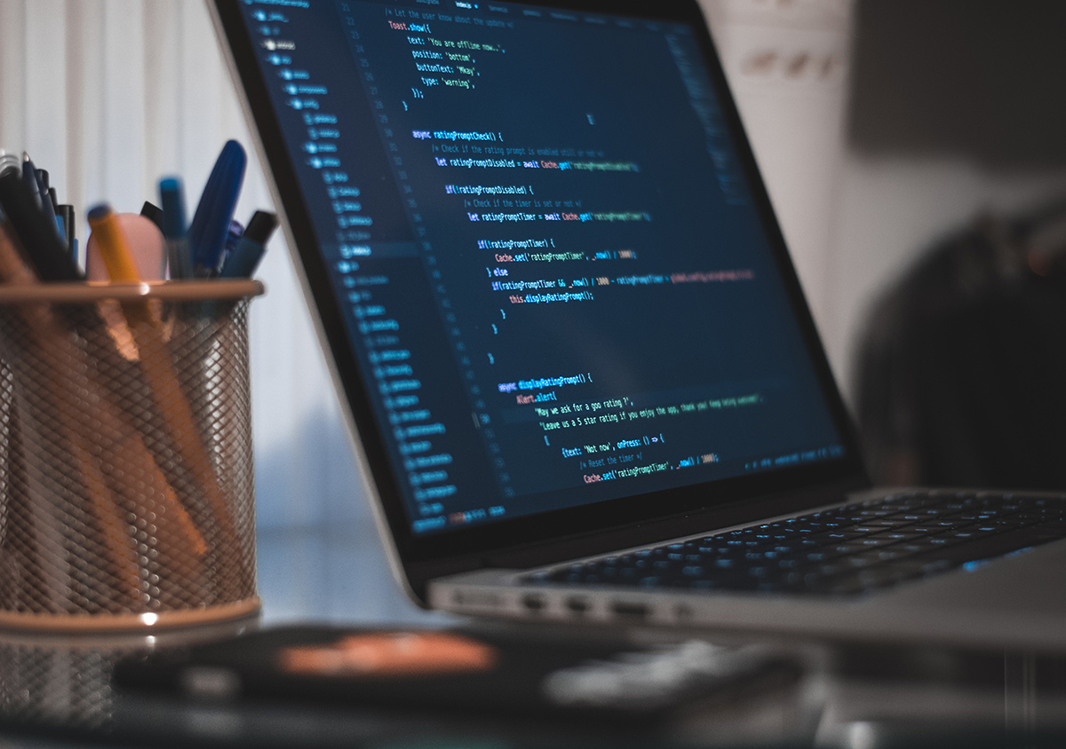 A computer on a table with lines of code on the monitor