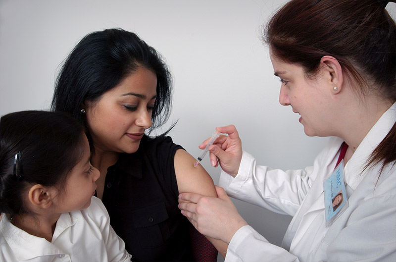 Woman and daughter getting a shot from doctor